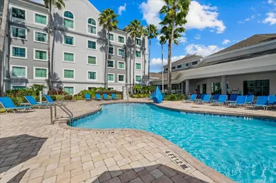 a swimming pool with blue lounge chairs and a building at Suite near Disney, free parking and shuttle to Parks in Orlando