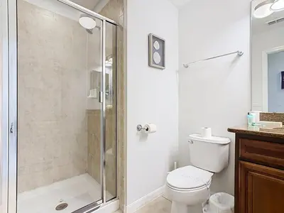 a bathroom with a toilet and a glass shower at Paradise Palms Disney Retreat 5BR Pool Home in Kissimmee