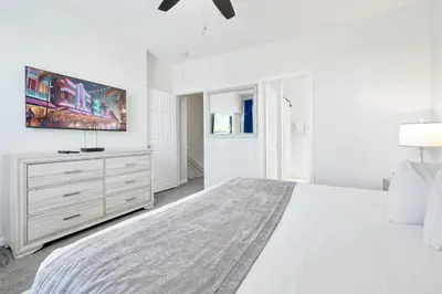 a white bedroom with a large bed and a dresser at Epic Universe Vacation Townhome, Vista Cay - 4035 in Orlando