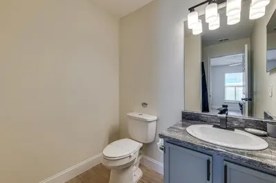 a bathroom with a toilet and a sink and a mirror at 10 Mi to Animal Kingdom Clermont Home with Pool! in Orlando