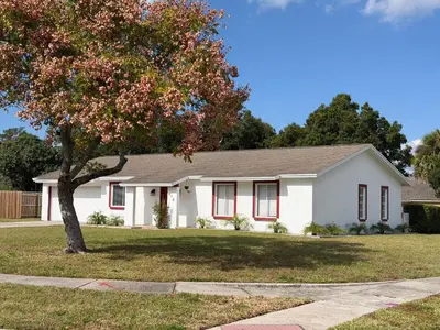 a white house with a tree in the front yard at Perfecto Mundo 2, Orlando Area 4BR-2B-Outdoor Pool-Jacuzzi-Billiard in Orlando