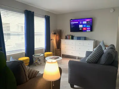 a living room with a couch and a tv on the wall at Sea World Orlando Apt - Minutes From Parks in Orlando