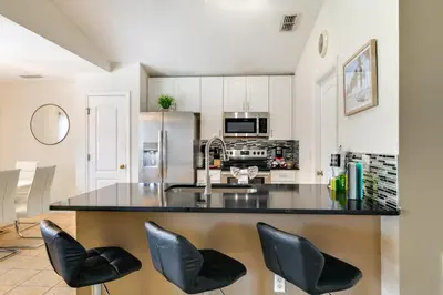 a kitchen with a large counter with black leather stools at Peaceful Clermont Gem with Pool, 9 Mi to Disney! in Orlando