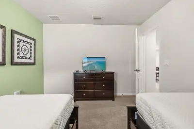 a bedroom with two beds and a tv on a dresser at Lavish Villa W Private Pool And Spa And Free Resort in Orlando