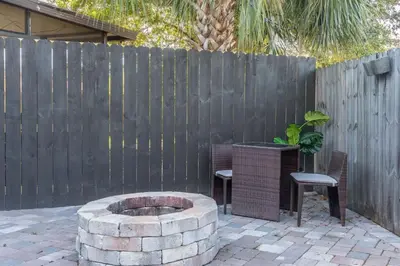 a backyard with a fire pit and two chairs and a fence at CUTE and COZY studio w jacuzzi in Orlando