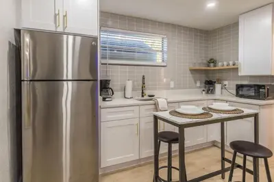 a kitchen with a stainless steel refrigerator and a table at CUTE and COZY studio w jacuzzi in Orlando