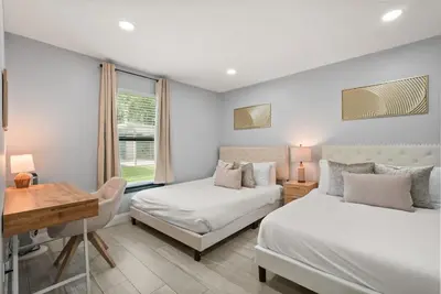 a bedroom with two beds and a desk and a desk at Modern Escape Near Lake Eola and Downtown Orlando in Orlando