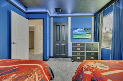 a blue room with two beds and a tv at Mahuna Matata in Kissimmee