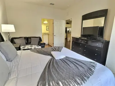 a bedroom with a large white bed and a television at Casa 3Q Lucaya Village — 15min da Disney in Kissimmee