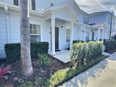 a white house with a palm tree in front of it at Casa 3Q Lucaya Village — 15min da Disney in Kissimmee