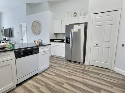 a kitchen with white cabinets and a stainless steel refrigerator at Casa 4Q c/ Piscina Aquecida — Lake Berkley in Kissimmee