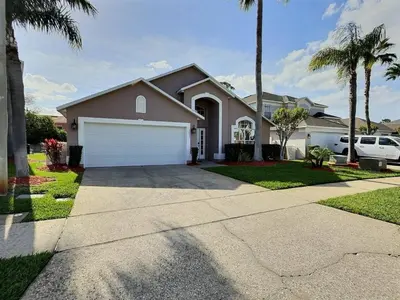 a house with a white garage and palm trees at Casa 4Q c/ Piscina Aquecida — Lake Berkley in Kissimmee