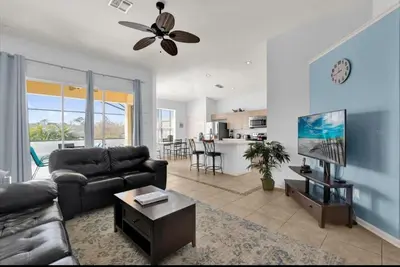 a living room with a couch and a tv and a kitchen at Mickeys Villa in Kissimmee