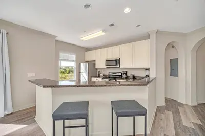 a kitchen with white cabinets and a counter with stools at Upstay Pet Friendly Condo 6 Minutes from Disney in Orlando