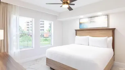 a white bedroom with a bed and two windows at Westgate Town Center Resort in Orlando