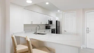 a white kitchen with a sink and two chairs at Westgate Town Center Resort in Orlando