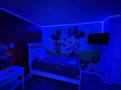 a bedroom with blue lights and a bed with a laptop at Family Home 20 min Disney 4BR Heated Pool BBQ in Kissimmee