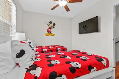 a bedroom with a red bed with mickey mouse pillows at Magic Home! GREAT Spot - 15Min Disney20 Universal in Kissimmee
