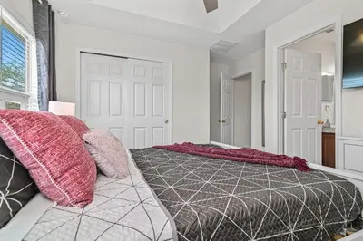 a bedroom with a large bed with pink and gray pillows at Magic Home! GREAT Spot - 15Min Disney20 Universal in Kissimmee