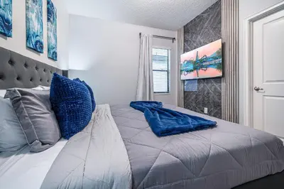 a bedroom with a large bed with blue pillows at Mansão 8Q Disney c/ Cinema, Game Room, Piscina in Orlando