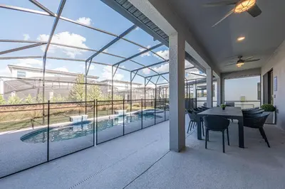 a patio with a table and chairs and a large window at Mansão 8Q Disney c/ Cinema, Game Room, Piscina in Orlando