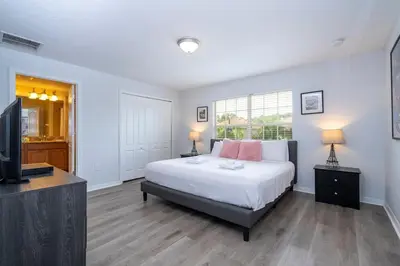 a bedroom with a bed and a flat screen tv at Paradise Palms - Spacious house and swimming pool in Kissimmee