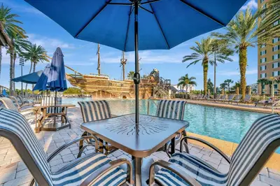 a table with chairs and an umbrella next to a pool at 2BR Fireworks View with Pool & Spa 5 Minutes to Disney in Orlando