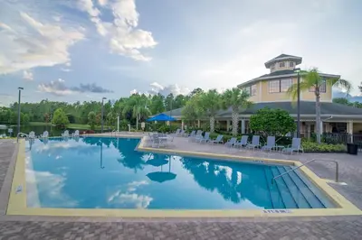 a pool at a resort with chairs and a building at Serene Gem, close to Disney- HEATEDsaltwaterPOOL in Kissimmee
