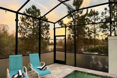 a house with a swimming pool and two chairs next to a house at Unplug in your private oasis-NEW corner Home Pool in Orlando