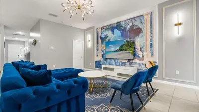 a living room with blue furniture and a chandelier at Upstay Bella Vida Retreat w Pool Cinema and Games in Kissimmee