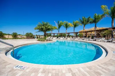 a large pool with chairs and palm trees at Casa 4Q West Lucaya – 5min da Disney in Kissimmee