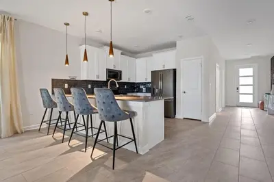 a kitchen with a island with blue bar stools at Casa 7Q Storey Lake c/ Piscina, Spa e Game Room in Kissimmee