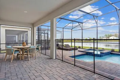 a house with a patio with a table and a pool at Casa 7Q Storey Lake c/ Piscina, Spa e Game Room in Kissimmee