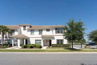 a large white house with a tree in front of it at Casa 5Q c/ Piscina Privativa - Storey Lake Resort in Kissimmee
