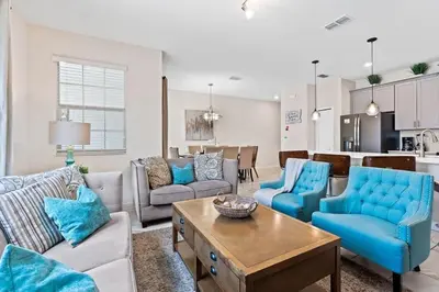a living room with blue furniture and a kitchen at Casa 4Q c/ Piscina Priv. no Storey Lake in Kissimmee