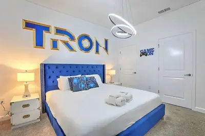 a bedroom with a blue bed with a iron sign on the wall at Let's Glo Now Adventure Cove Villa townhouse in Kissimmee