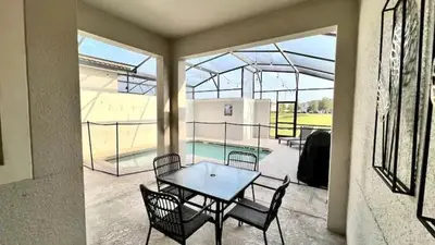 a patio with a table and chairs and a pool at Let's Glo Now Adventure Cove Villa townhouse in Kissimmee