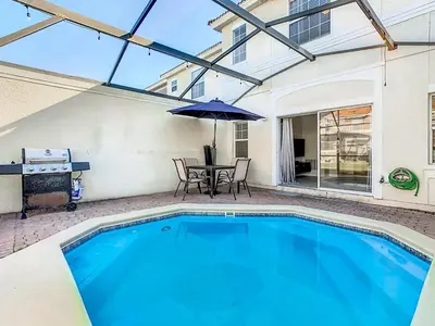 a swimming pool with a table and an umbrella at Cozy Townhouse with Private Pool in Kissimmee in Kissimmee