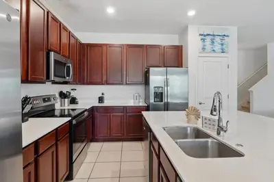 a kitchen with wooden cabinets and a stainless steel refrigerator at Lake Side View Private Pool Home In Resort! villa in Kissimmee