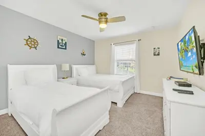 a white bedroom with two beds and a window at Beautiful Paradise Palms Retreat townhouse in Kissimmee