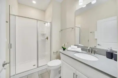 a white bathroom with a shower and a toilet at Retreat & Relax Screened In Pool Home Kid Rooms townhouse in Kissimmee