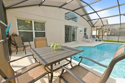 a patio with a table and chairs and a pool at Casa 5Q c/ Piscina Priv. e Sala de Jogos in Kissimmee