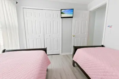a bedroom with two beds and a tv on the wall at Casa 5Q c/ Piscina Priv. e Sala de Jogos in Kissimmee