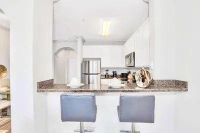 a kitchen with white cabinets and blue chairs at Upstay Pet-Friendly Condo with Pool in Orlando