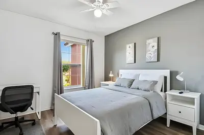 a bedroom with a white bed and a chair at Casa Aconchegante no Lake Berkley – Perto da Disney in Kissimmee