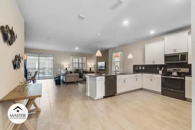 a large kitchen with white cabinets and a living room at 9 Bedrooms 5 Bathrooms Storey Lake home in Kissimmee