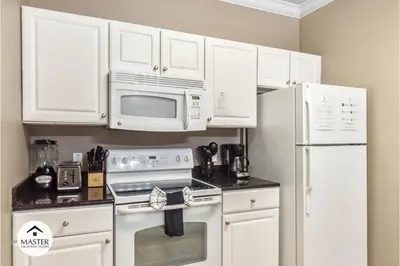 a kitchen with white cabinets and a stove and microwave at 3 Bedrooms 2 Bathrooms Lucaya Village townhouse in Kissimmee