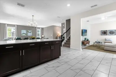 a kitchen with brown cabinets and a living room at 7 Bedroom 6 Bathrooms Storey Lake Resort home in Kissimmee