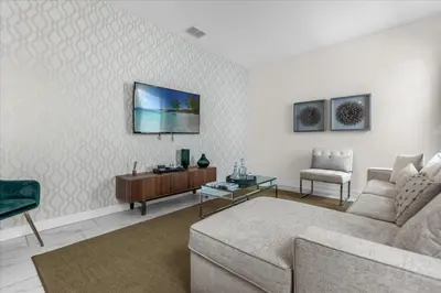 a living room with a couch and a tv on a wall at 7 Bedroom 6 Bathrooms Storey Lake Resort home in Kissimmee