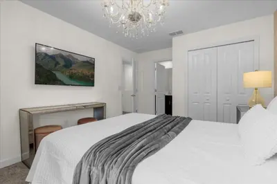 a bedroom with a white bed and a chandelier at 7 Bedroom 6 Bathrooms Storey Lake Resort home in Kissimmee